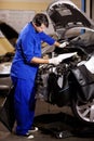 These numbers make no sense. A male mechanic reading some papers while working on the engine of a car.