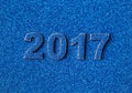 Numbers of the new year 2017 laid out on background of blue sparkling shining sequins.