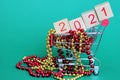 The numbers 2021 in a supermarket toy cart . New year`s number 2021 in red numbers on wooden blocks among Christmas beads Royalty Free Stock Photo