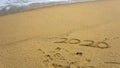 Numbers 2020 year on the sea shore, message handwritten in the golden sand on beautiful beach background Royalty Free Stock Photo