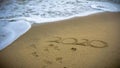 Numbers 2020 year on the sea shore, message handwritten in the golden sand on beautiful beach background Royalty Free Stock Photo