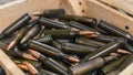 Numerous black rifle bullets with copper-coloured endings placed in a wooden box. Closeup shot. Military. Gun range