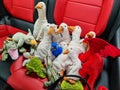 Numerous stuffed animals such as geese, ducks, crocodiles and dragons sit together on red leather seats