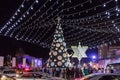 Numerous tourists view the Christmas tree decorated with toys, the Christian cross, the Judean Menorah, and the Muslim Crescent in