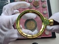 Numismatist closeup examines a coin with magnifying glass