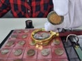 Numismatist in white gloves examines ancient coins collection at table