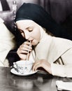 Nun sipping tea out of a teacup with a straw Royalty Free Stock Photo
