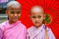 Nuns in pink robes with red paper umbrella