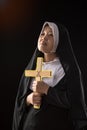 Nuns praying to the GOD while holding a crucifix symbol with golden light in black background Royalty Free Stock Photo