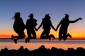 Silhouette of happy girls friends jumping in the air holding hands during sunset Royalty Free Stock Photo