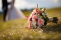 Nuptial scene Wedding bouquet rests on grass with married couple Royalty Free Stock Photo