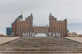 Landscape of Nur Sultan City with monumental Gate with towers and Nur Sultan logo.