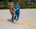 A nurse accompanies an elderly blind woman on a walk.