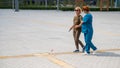 A nurse accompanies an elderly blind woman on a walk.