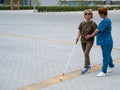 A nurse accompanies an elderly blind woman on a walk.