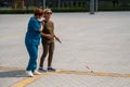 A nurse accompanies an elderly blind woman on a walk.