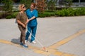 A nurse accompanies an elderly blind woman on a walk.