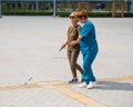 A nurse accompanies an elderly blind woman on a walk.