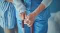 a nurse aids an elderly woman in standing up, their hands firmly gripping her walking stick, both dressed in a blue