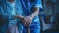 a nurse aids an elderly woman in standing up, their hands firmly gripping her walking stick, both dressed in a blue