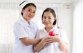 Nurse and Asian elderly woman holding heart red model on hands together,Senior healthy and taking care concept