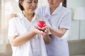 Nurse and Asian elderly woman holding heart red model on hands together,Senior healthy and taking care concept Royalty Free Stock Photo