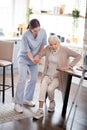 Nurse assisting aged woman in making steps after surgery