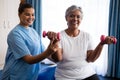 Nurse assisting senior woman in lifting dumbbells Royalty Free Stock Photo