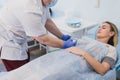 Nurse attaching intravenous tube to patient`s hand in hospital bed