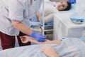 Nurse attaching intravenous tube to patient`s hand in hospital bed