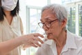 Nurse or caregiver gives water to senior woman,taking care,feeding water,thirsty asian old elderly drinking fresh water to quench Royalty Free Stock Photo