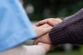 Nurse or caregiver hold hand of elderly patients to support and soothe walk by using walker in garden Royalty Free Stock Photo