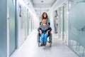 Nurse carrying a woman in wheelchair along the hospital