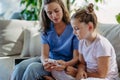 Nurse checking girl's blood glucose level using a fingerstick glucose meter.