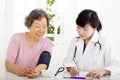 Nurse checking senior woman blood pressure