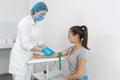 A nurse in the clinic inserts a catheter into a vein for blood testing for a young girl