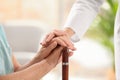 Nurse comforting elderly woman with cane against blurred background. Assisting senior generation