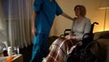 Nurse comforting senior woman in wheel chair assistance and help in nursing home