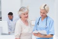 Nurse communicating with patient while doctor using computer Royalty Free Stock Photo