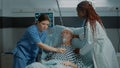 Nurse consulting sick patient in hospital ward at clinic