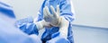 Nurse or doctor put surgical glove on surgeon \'s hand inside operating room in hospital.