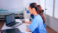 Nurse of doctor typing on laptop sitting at desk in cabinet Royalty Free Stock Photo