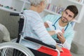 Nurse doing bandages on old lady on wheelchair