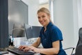 Nurse on Duty working on computer at the Reception Desk in modern clinic and looking camera Royalty Free Stock Photo