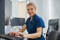 Nurse on Duty working on computer at the Reception Desk in modern clinic and looking camera Royalty Free Stock Photo