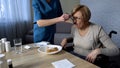 Nurse feeding old disabled female in wheelchair medical support and care sadness