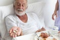 Nurse give medicine pills to elderly senior patient while he is in his bed with breakfast Royalty Free Stock Photo