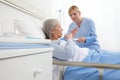 Nurse gives the pill to the elderly woman patient lying in the hospital room bed, concept of loneliness and old age diseases
