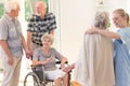 Elderly man supporting disabled wife