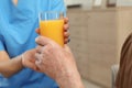 Nurse giving glass of juice to elderly man indoors. Assisting senior people Royalty Free Stock Photo